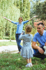 Obraz premium family shot in the park, summer day. mom, dad, daughter have fun day off. Mom and Dad are wearing a denim suit. smart girl