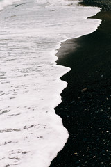 a sea wave arrives on the shore with black volcanic sand . beautiful natural background in Iceland