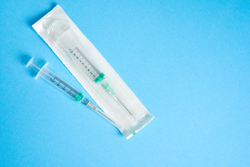 Obraz premium Two plastic disposable medical syringes open and package lie on blue background.