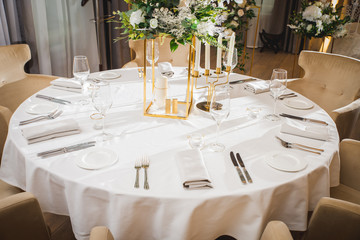 Glasses, flower fork, knife served for dinner in restaurant with cozy interior