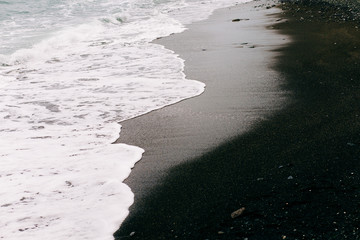 a sea wave arrives on the shore with black volcanic sand . beautiful natural background in Iceland