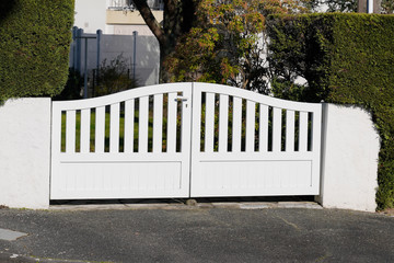 white new metal driveway entrance home gates in modern suburb house