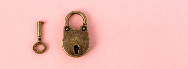 bronze key and padlock on gently pink paper, panoramic mock-up