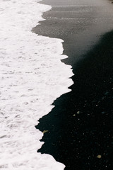 a sea wave arrives on the shore with black volcanic sand . beautiful natural background in Iceland