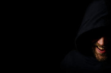 evil face a man in the dark. beard smile