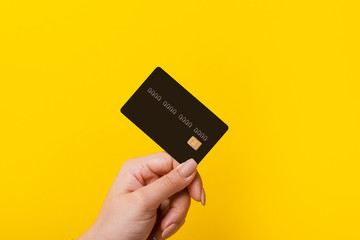 Female hand holding credit card on yellow background - 321909464