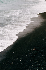a sea wave arrives on the shore with black volcanic sand . beautiful natural background in Iceland