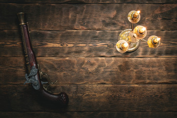 Old musket gun on pirate desk table in the light of burning candle concept background with copy...