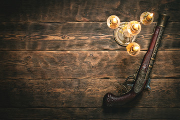 Old musket gun on pirate desk table in the light of burning candle concept background with copy...