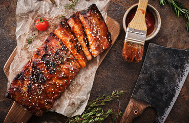 Delicious barbecued ribs seasoned with a spicy basting sauce and served on chopping board.