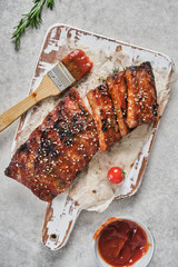Delicious barbecued ribs seasoned with a spicy basting sauce and served on chopping board.