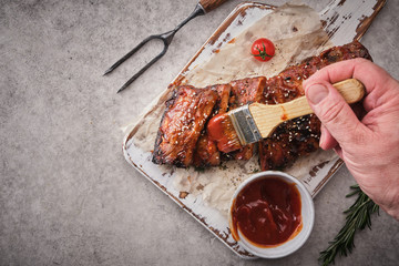 Delicious barbecued ribs seasoned with a spicy basting sauce and served on chopping board.