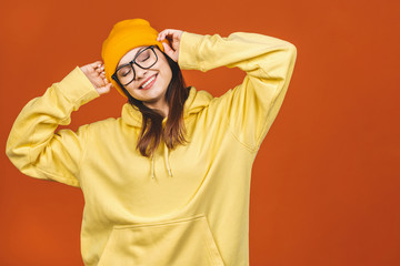 Fototapeta na wymiar People, youth, leisure and lifestyle concept. Fashionable beautiful young Caucasian young female student wearing stylish clothing laughing, pointing finger. Isolated over orange. 