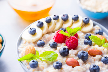 Healthy breakfast. Bowl of oatmeal porridge with fresh blueberries, raspberries, almonds and banana. Clean eating, dieting, detox, vegetarian food concept. Healthy concept
