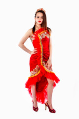 Beautiful brunette adult girl in a red silk chic, luxurious dress wearing gold with red stones crown standing and posing on white background. Isolate