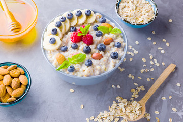 Healthy breakfast. Bowl of oatmeal porridge with fresh blueberries, raspberries, almonds and banana. Clean eating, dieting, detox, vegetarian food concept. Healthy concept