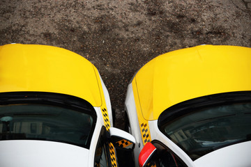 Two yellow taxi cars standing together with dark windows