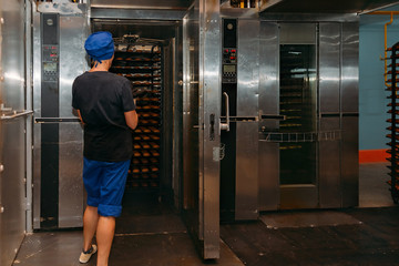Confectionery manufacturing. Baker puts cookies into oven for baking