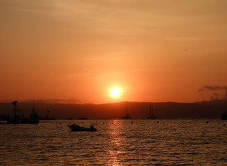 Naklejka na ściany i meble sunset reflecting on the sea. Boats in the beach of Paracas/Peru.