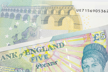 A five pound British pound sterling with a red, five Euro European bank note close up in macro