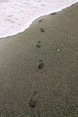 footprints on the wet sand from the sea wave on the beach