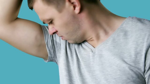 Man With Sweaty Armpit Covering His Nose With Hand. Bad smells concept.