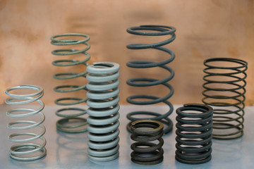 Set of springs of different size and different material on a steel surface on a copper plate background. 