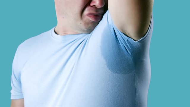 Young man having problem sweat under armpit. Young man sniffing his armpit, something stinks very bad. Bad smells concept.
