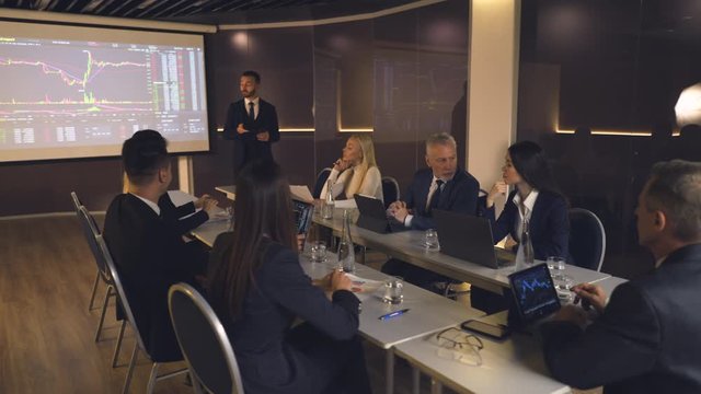 The businessman standing near the large screen and speaking