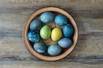 Different easter eggs in bowl on a wooden background