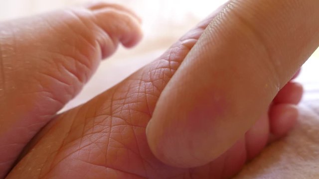 Close up footage of a babies feet, her dad gently touching with his finger babies sole...