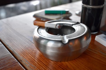A smoking cigarette left on an ashtray