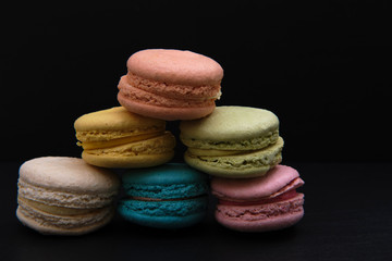 Set of many macaroni multicolored. Delicious macaroons on black background. French sweet cookie