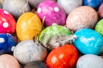 Different easter eggs with straw on wooden plate on blue table