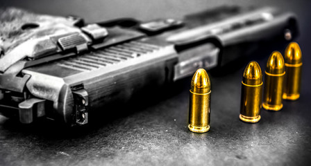 Bullets and handcuffs. Close-up of 9mm pistol. Gun and weapon with bullets amunition on black...