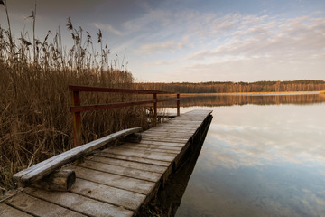 Fototapeta na wymiar Old wooden footbridge on the lake
