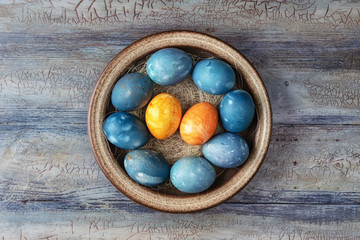 Different easter eggs in bowl on a wooden background