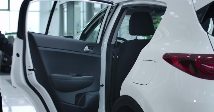 Young Caucasian chauffeur getting out of the car and opening door for adult blond businesswoman. Professional driver working for successful businesswoman. Cinema 4k ProRes HQ.