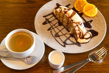 Apple strudel with sauce and coffee on wood table