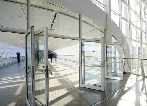 Hamburg, Germany, February 05, 2020: Pedestrian bridge made of steel and glass connects two buildings of the Hamburg exhibition halls, some people in motion blur are walking through