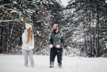 Fototapeta na wymiar Couple playing with snow in the forest