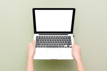 A laptop with a white screen in female hands on a green background. Open computer with empty copy space for text message.