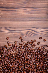 Roasted coffee beans on a brown wooden background with copyspace. Flat lay.