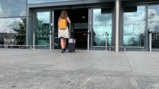 A woman Walking to an airport with her luggage