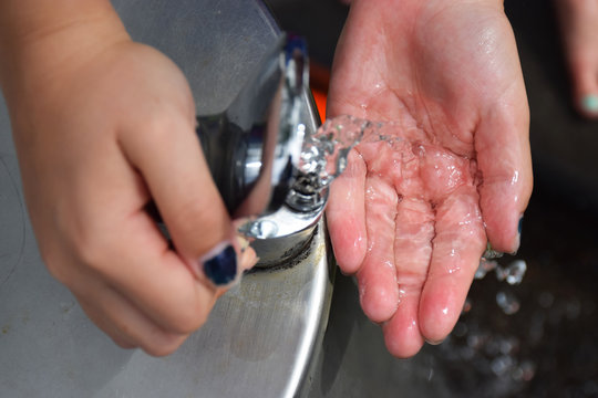 Water from a drinking fountain cascades across the hand of a young girl