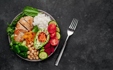 Bowl Buddha. rice, chicken breast, broccoli, pumpkin, avocado, chickpeas, carrots, cucumber, beets, a stone background  with copy space for your text