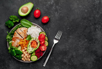 Bowl Buddha. rice, chicken breast, broccoli, pumpkin, avocado, chickpeas, carrots, cucumber, beets, a stone background  with copy space for your text