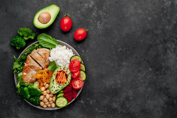 Bowl Buddha. rice, chicken breast, broccoli, pumpkin, avocado, chickpeas, carrots, cucumber, beets, a stone background  with copy space for your text