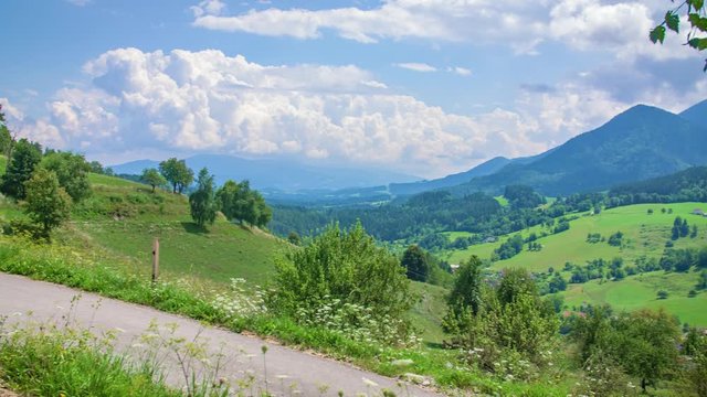 Pan overview of beautiful nature with cumulus clouds in the sky.Couples cycling along with the countryside.
