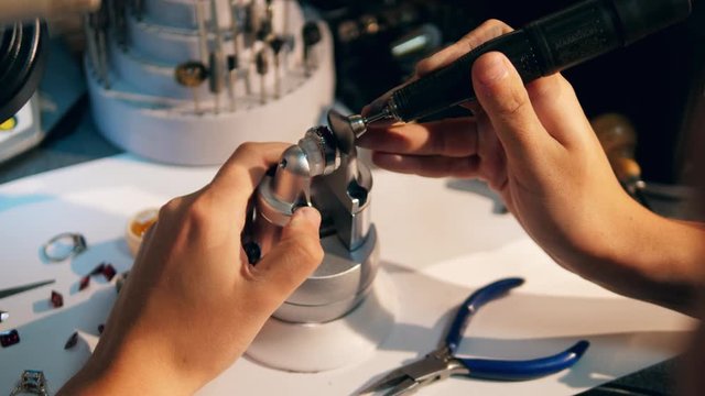 Male jeweller polishes a ring with red gemstone. A goldsmith in jewelry working with ring.